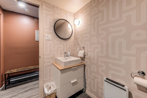 Un baño con lavamanos, espejo, toallero y retrete.