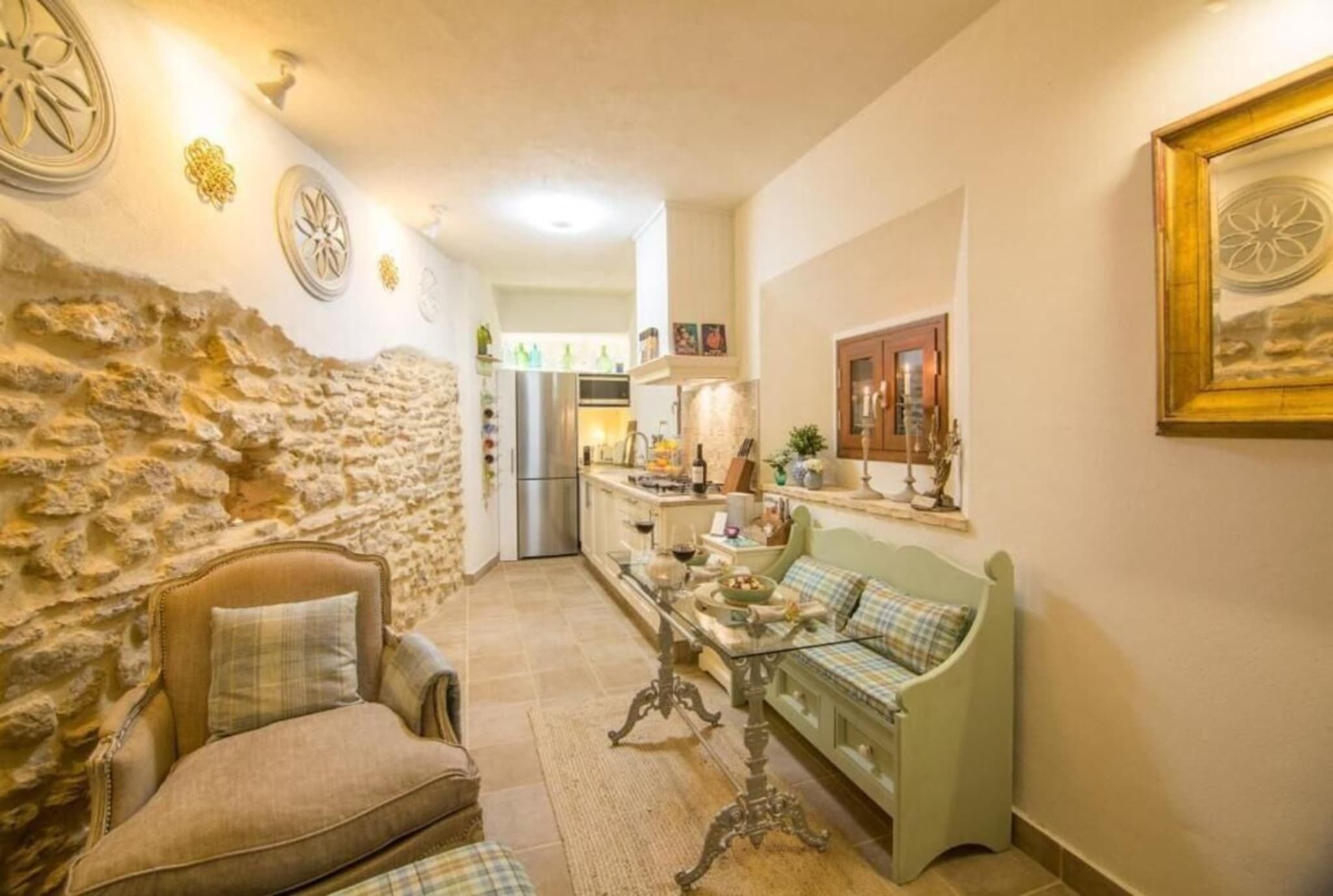 A cozy interior with a stone wall, a sofa, a table, and a kitchen in the background.