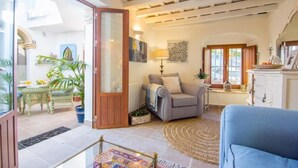 A living room with a sofa, a chair, a lamp, and a view of the outside. - Casa La Muralla: a romantic boutique house by the historic walls of Medina Sidonia (Medina-Sidonia)