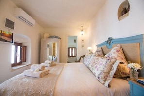 Un dormitorio con cama, armario, espejo, mesita de noche con lámpara y ventana.