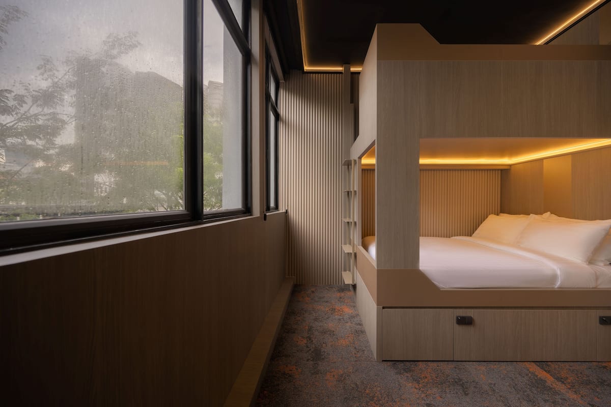 Una habitación moderna con literas, ventanas amplias y vistas al exterior.