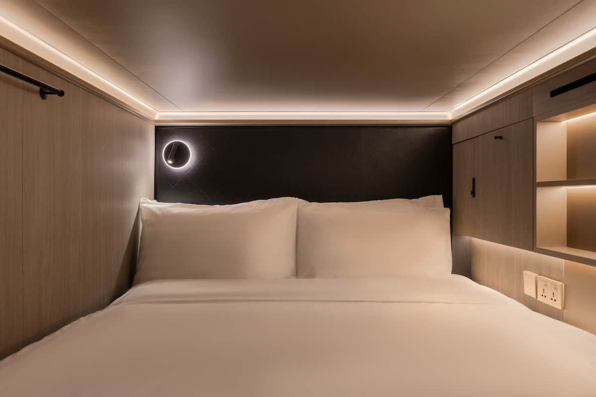 Un dormitorio moderno con cama, armario empotrado y lámpara circular en la pared.
