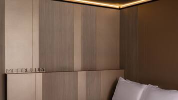A modern bedroom with a large bed, built-in headboard, and a recessed ceiling light.
