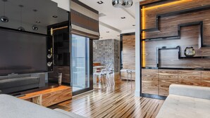 A modern living room with a large flat-screen TV, wooden flooring, and a glass door leading to a balcony. - Imperial Apartments - Na Fali (Sopot)