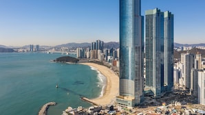 A coastal cityscape with modern skyscrapers, a beach, and a clear blue sky. - LCT Residence Y Collection (Busan)