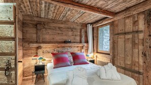 Una habitación rústica de madera con una cama, almohadas y toallas.