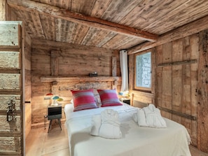 Um quarto rústico de madeira com cama, almofadas e toalhas.