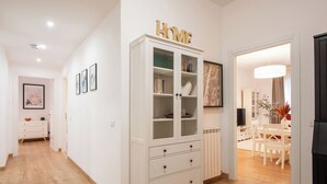 A hallway with a white cabinet, a dining area with a table and chairs, and a framed picture on the wall. - Monteverde Prestige (Roma)