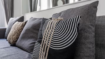 A sofa with multiple cushions, including a black and white striped pillow and a woven pillow.