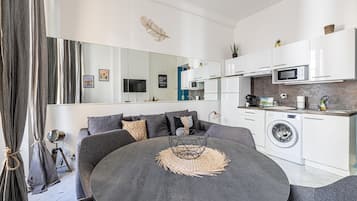 A modern living room with a round table, grey sofa, and a built-in washing machine.