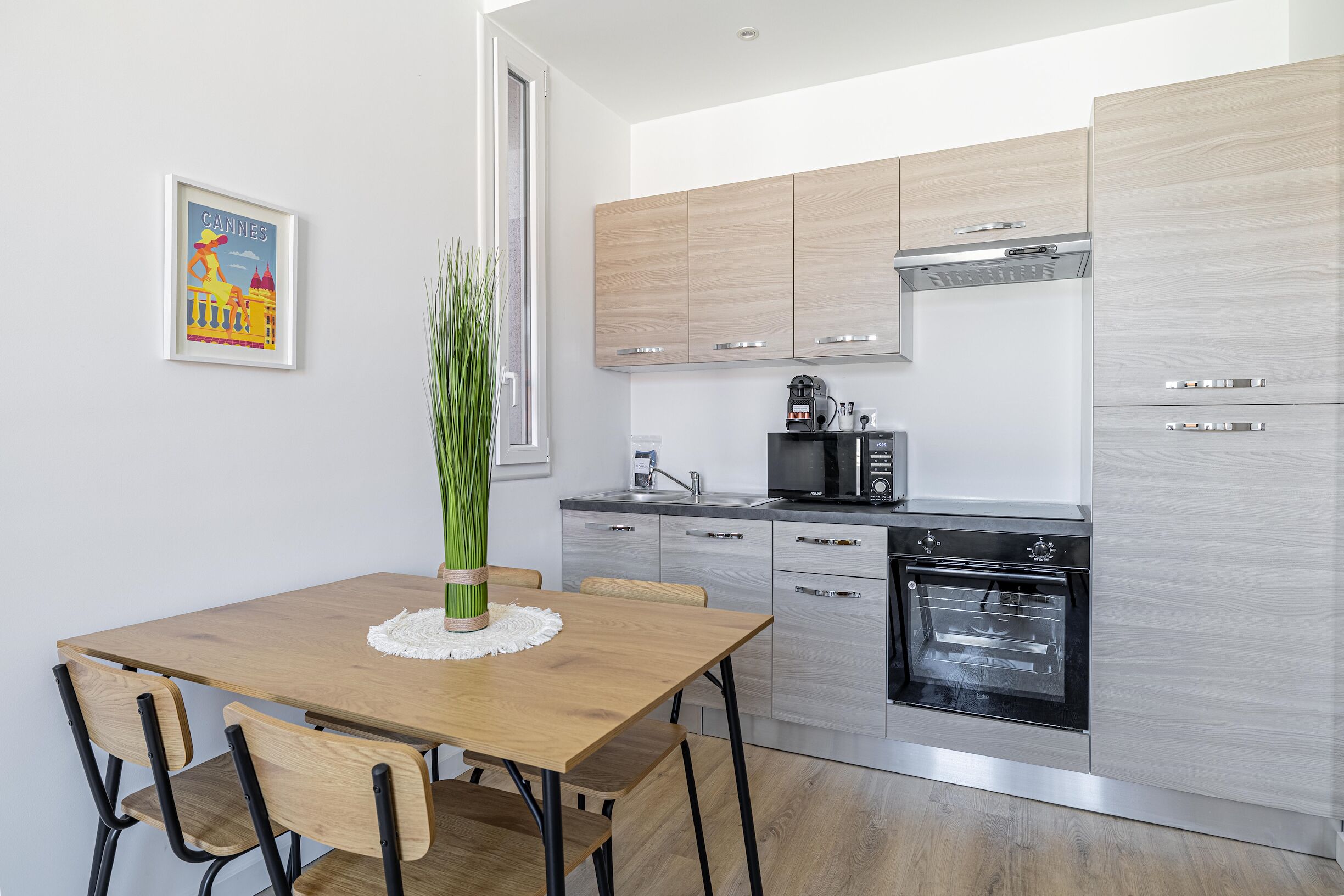 A modern kitchen with wooden cabinets, a built-in oven, and a dining area with a wooden table and chairs.