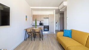 Una sala de estar moderna con un sofá, una mesa de comedor con sillas y una cocina al fondo.