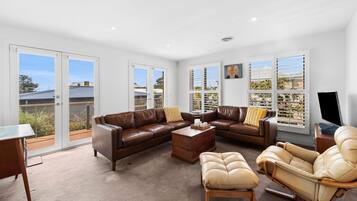 A spacious living room with a brown leather sofa, a beige armchair, and a wooden coffee table.
