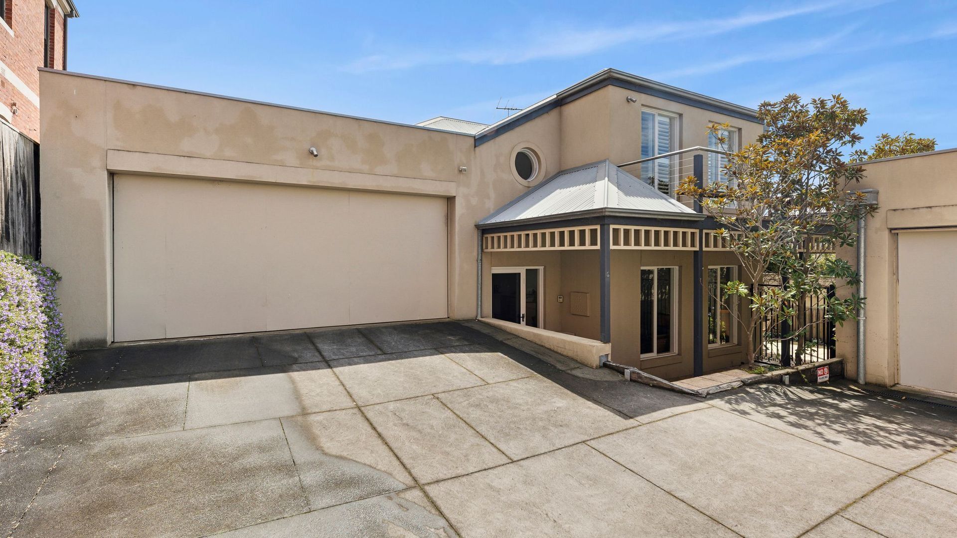A residential building with a garage, a covered patio, and a small garden area.