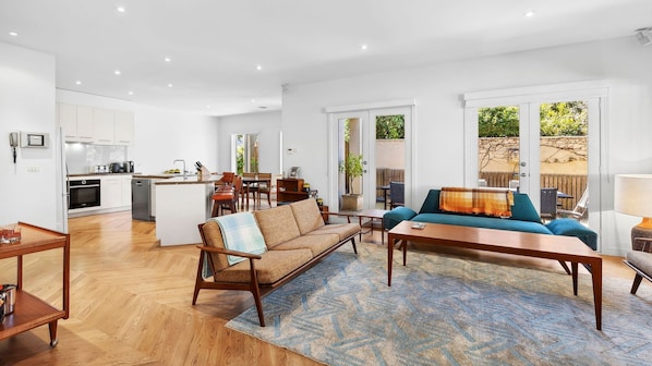 Un espacio habitable moderno y abierto con cocina, comedor y una zona de estar acogedora con sofá y mesa de centro.