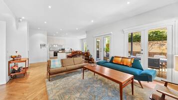 A spacious living area with a sofa, coffee table, and a kitchen in the background.