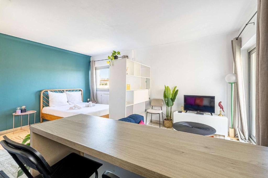 Ein modernes Hotelzimmer mit einem Bett, einem Schreibtisch, einem Fernseher und einer Pflanze.