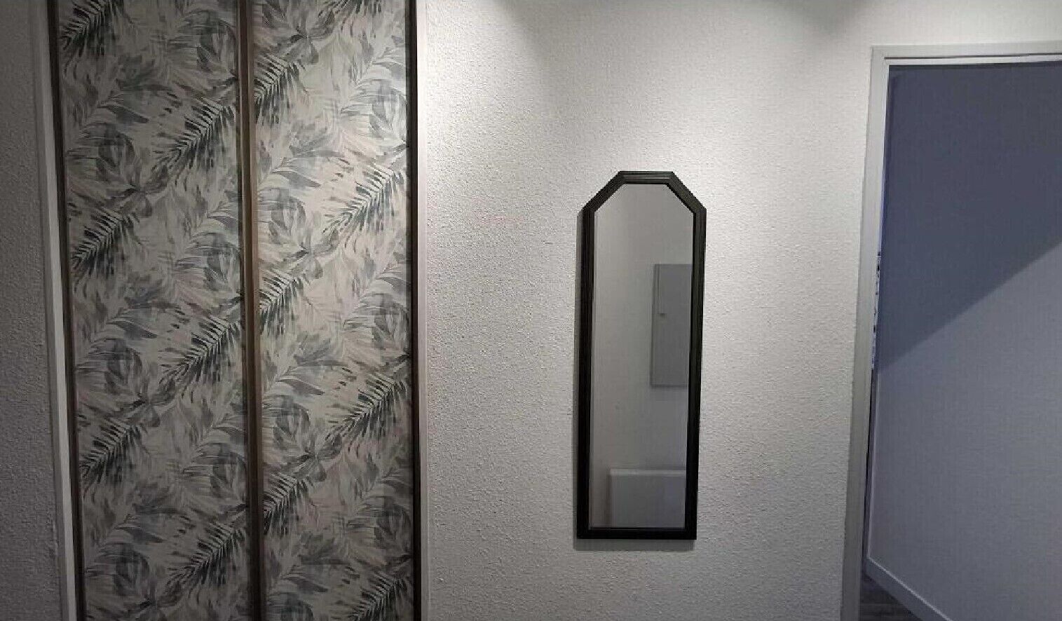 Ein Flur mit Wandspiegel und strukturierten Tapeten.