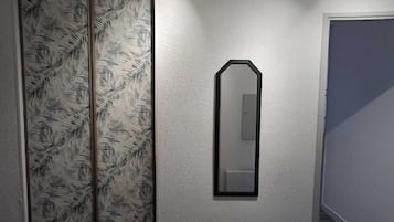 A hallway with a mirrored wall and patterned wallpaper.