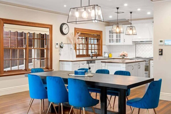 Eine moderne Küche mit weißen Schränken, einer Holztischinsel und blauen Stühlen um einen zentralen Tisch.