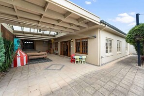 A covered patio area with a wooden bench, a small table, and a red and white striped tent.
