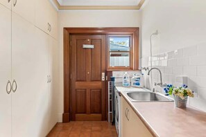 A compact kitchen with a wooden door, a window, a sink, and a countertop with a flower vase.
