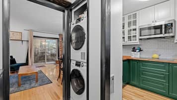Une cuisine moderne avec des meubles blancs, un four à micro-ondes et un lave-linge placés dans un coin.