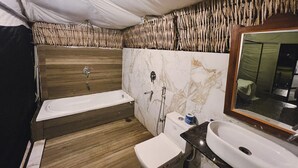 Een badkamer met een houten wastafelmeubel, een marmeren wastafel en een bad.