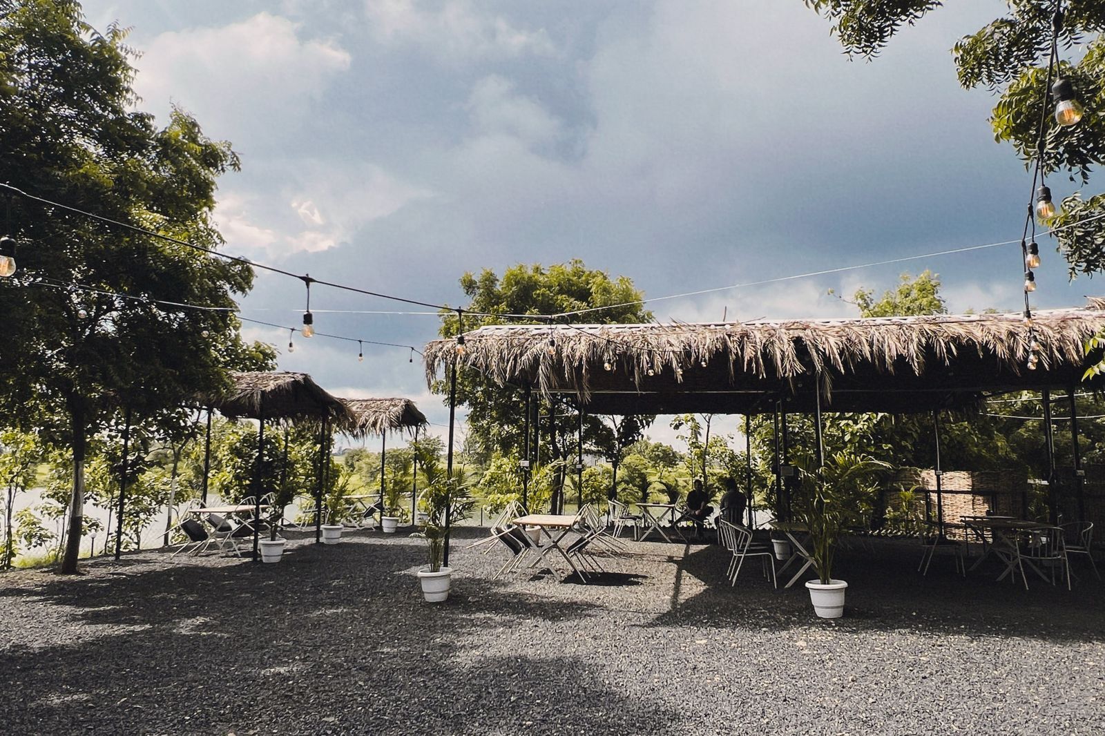 Een buitenzitgedeelte met rieten parasols, planten in potten en lichtslingers.