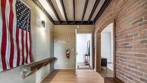 A hallway with a wooden bench, a fire extinguisher, and a door leading to another room.