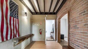 A hallway with a wooden bench, a fire extinguisher, and a door leading to another room.