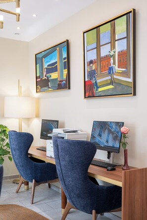 A modern office space with two desks, computers, chairs, and framed artwork on the wall.
