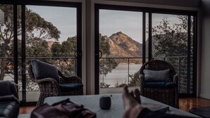 A balcony with wicker chairs and a table, overlooking a mountainous landscape and a body of water. - Sentinel at Freycinet (Glamorgan-Spring Bay)