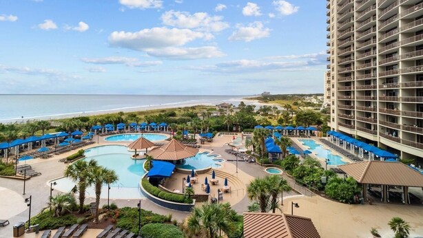 Un resort con diverse piscine, vista sulla spiaggia e un grande edificio alberghiero.