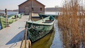 Une jetée en bois avec des bateaux, une petite cabane et un lac paisible.