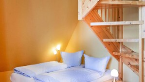 Une chambre à coucher avec un lit, deux lampes de chevet, une table de chevet et un escalier en bois.