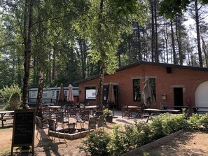 Un área de estar al aire libre con mesas y sillas, un edificio de ladrillo y un cartel.