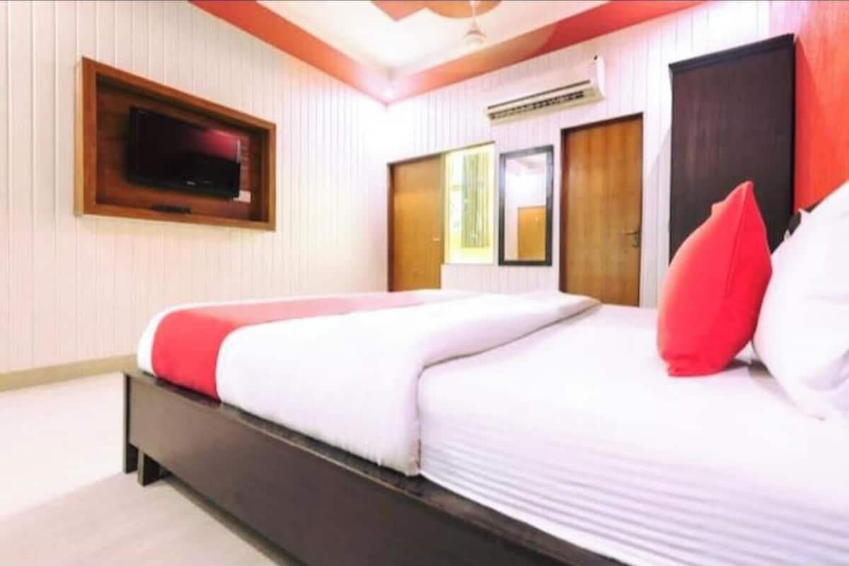 Ein Hotelzimmer mit einem Bett, einem an der Wand befestigten Fernseher und einer Tür.