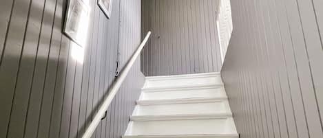 Un escalier avec une rampe, des murs en bois et un luminaire au plafond.