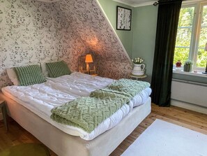 A bedroom with a bed, pillows, a bedside lamp, a window with a view, and a radiator. - 7 Person Holiday Home in Horn (Horn)