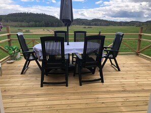 A wooden deck with a table and chairs, overlooking a green landscape. - 7 Person Holiday Home in Horn (Horn)