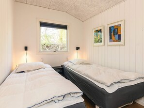 A room with two beds, a window with blinds, two wall-mounted lamps, and two framed artworks. - 8 Person Holiday Home in Rodby (Rodby)