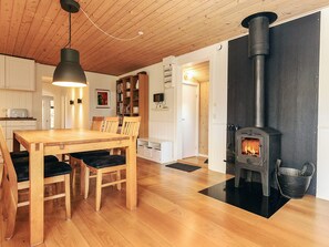 A cozy room with a wooden table and chairs, a black stove, and a bookshelf. - 8 Person Holiday Home in Rodby (Rodby)
