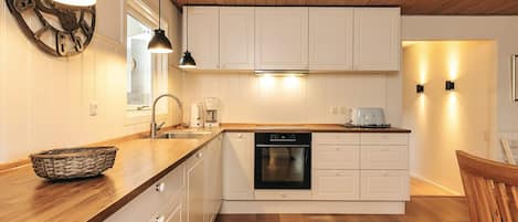 A modern kitchen with wooden cabinets, a dishwasher, and a dining area with a wooden table and chairs.
