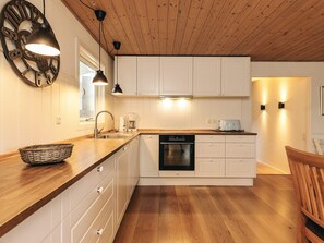 A modern kitchen with wooden cabinets, a dishwasher, and a dining area with a wooden table and chairs. - 8 Person Holiday Home in Rodby (Rodby)