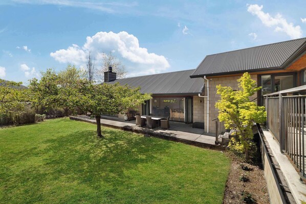 Una casa moderna con un patio, césped y un árbol.