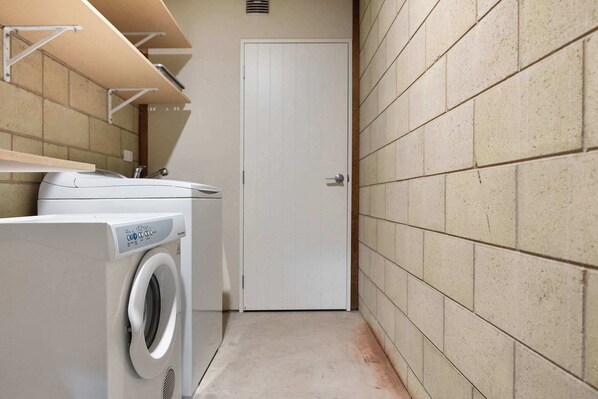 A laundry room with a washing machine, a door, and tiled walls. - Wanaka Family Retreat (Wānaka)