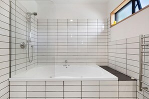 Ein modernes Badezimmer mit einer gläsernen Duschkabine, einer weißen Badewanne und Fliesenwänden.