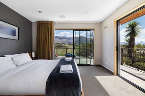 Ein Hotelzimmer mit einem großen Bett, Bergblick und einem Balkon mit Geländer.