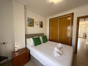 Ein Hotelzimmer mit einem Bett, einem Nachttisch, einer Lampe, einem Kleiderschrank und Kunstwerken an der Wand.